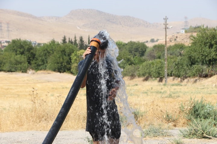 Sıcaktan bunalan vatandaş tarım sulama hortumu ile serinledi